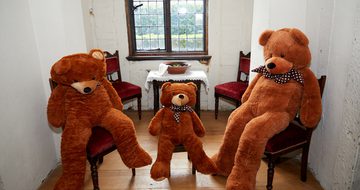 The three large teddy bears sitting on chairs.