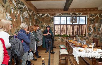 A group of people on a tour in a Tudor dining room.