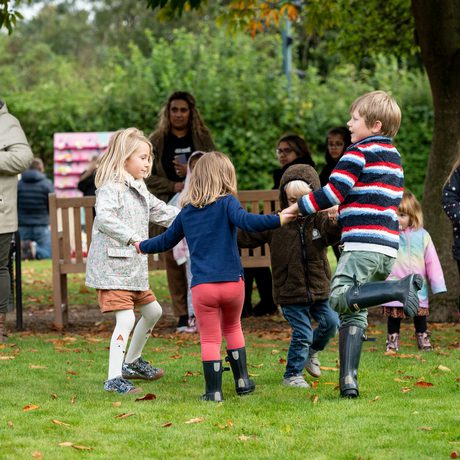 A group of children holding hands in a circle and dancing.