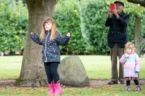 Children in a garden. An adult is taking a photo behind them.