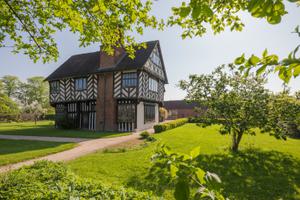 Tudor timber-framed house in garden surrounded by trees