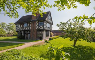 Tudor timber-framed house in garden surrounded by trees