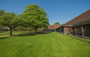 The green lawn area with a few trees. To the right is part of the visitor centre.