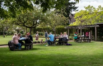 Visitors sitting on picnic benches in the gardens.