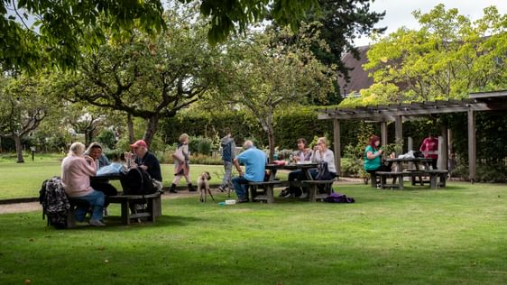 Visitors sitting on picnic benches in the gardens.