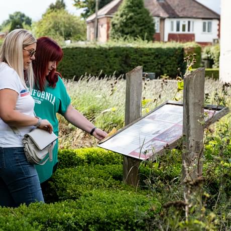 Two ladies reading an information board in the garden.