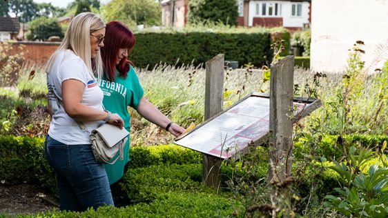 Two ladies reading an information board in the garden.
