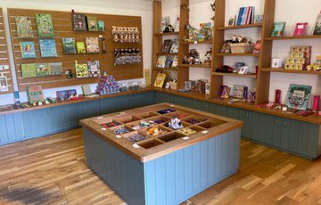 Small shop with wooden shelves displaying various packaged goods and jars.