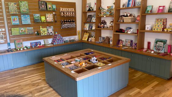 Small shop with wooden shelves displaying various packaged goods and jars.