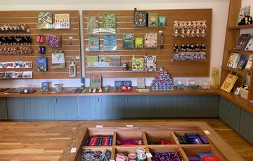Small shop with wooden shelves displaying various packaged goods and jars.