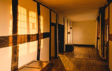 A long wooden gallery at dusk with sun setting through the windows.