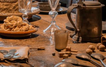 Close up of glasses, jug and and plates on a wooden historic table.