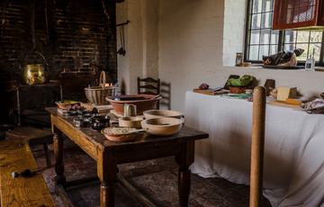 Close up of items on a table and sideboard in a Tudor kitchen.