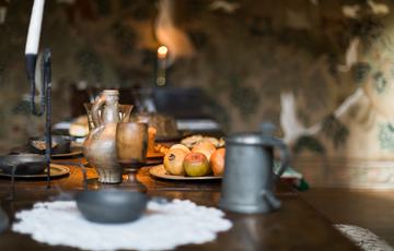 Close up of historic metal mugs and candle on a table.