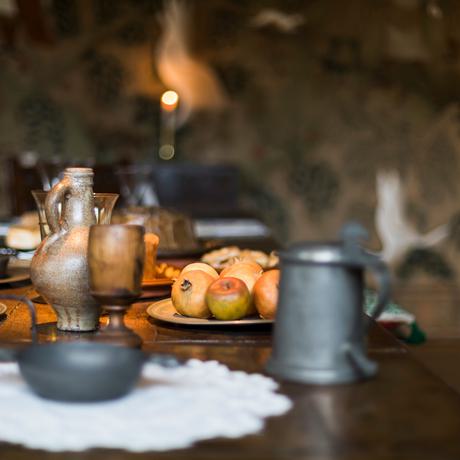 Close up of historic metal mugs and candle on a table.