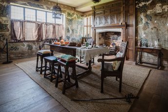 Dining room table surrounded by chairs and stools in front of unlit fireplace