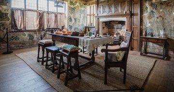 Dining room table surrounded by chairs and stools in front of unlit fireplace