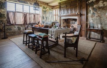 Dining room table surrounded by chairs and stools in front of unlit fireplace