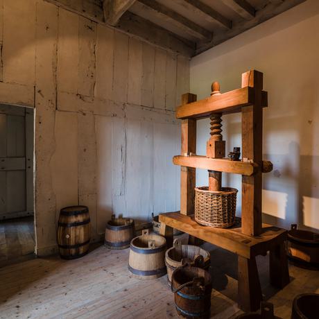 A small room with wooden barrels and large equipment.