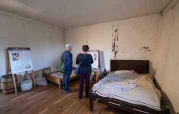 Visitors in a servants bedroom with two beds.
