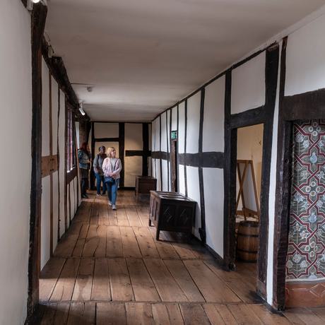 The Long Gallery with visitors at the end of the wooden hallway.