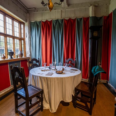 A small room with red and blue fabric hung around the room and small circular table with chairs in the centre.