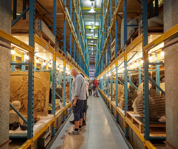 Racks in a large storage area containing stone sculptures