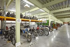 Large storage room containing vintage motorcycles and cars