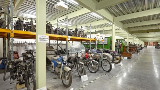 Large storage room containing vintage motorcycles and cars