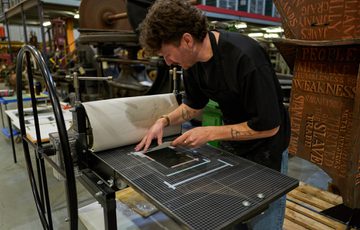 A person carefully preparing a printing plate on a press.