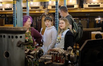 An adult and two children looking at museums objects on open display.