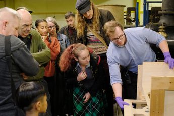 A staff member unboxes an artwork as a group of people watch.