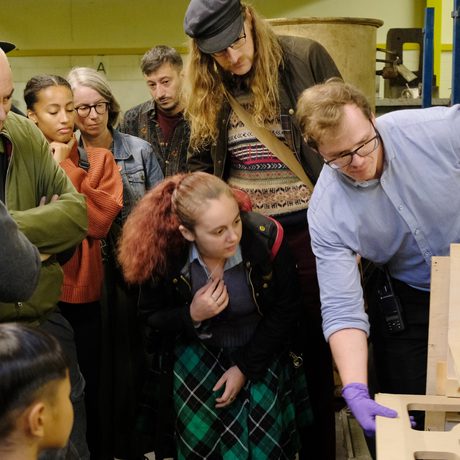 A staff member unboxes an artwork as a group of people watch.