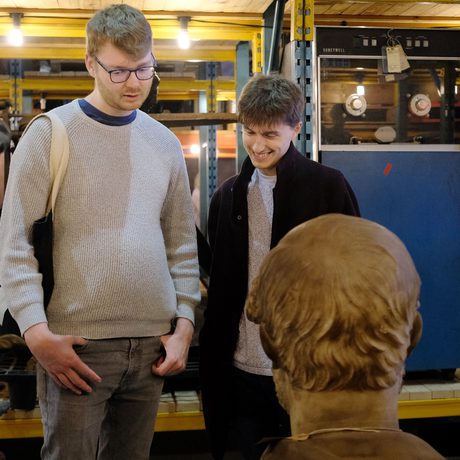 Two people looking at a bust that is on open display and stored on warehouse shelves.