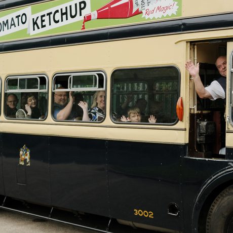 People waving while travelling on a vintage bus.