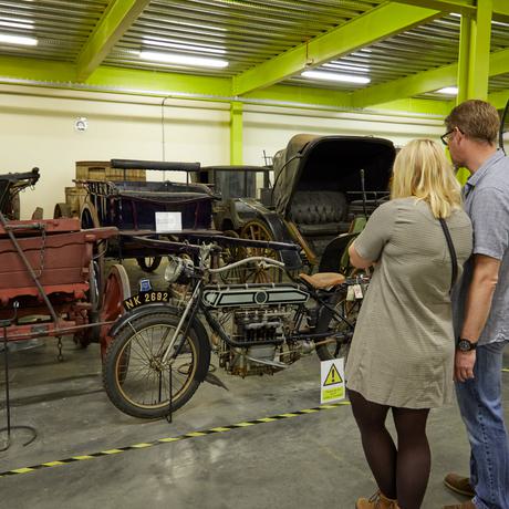 Two adults looking at a collection of bikes and vehicles.