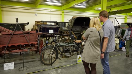 Two adults looking at a collection of bikes and vehicles.