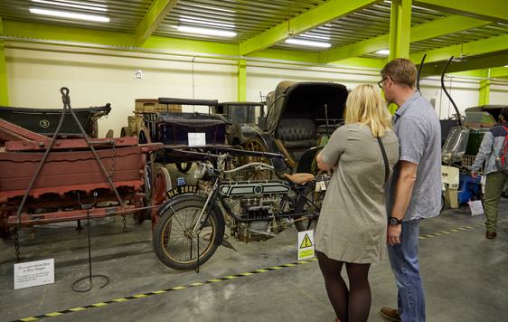 Two adults looking at a collection of bikes and vehicles.