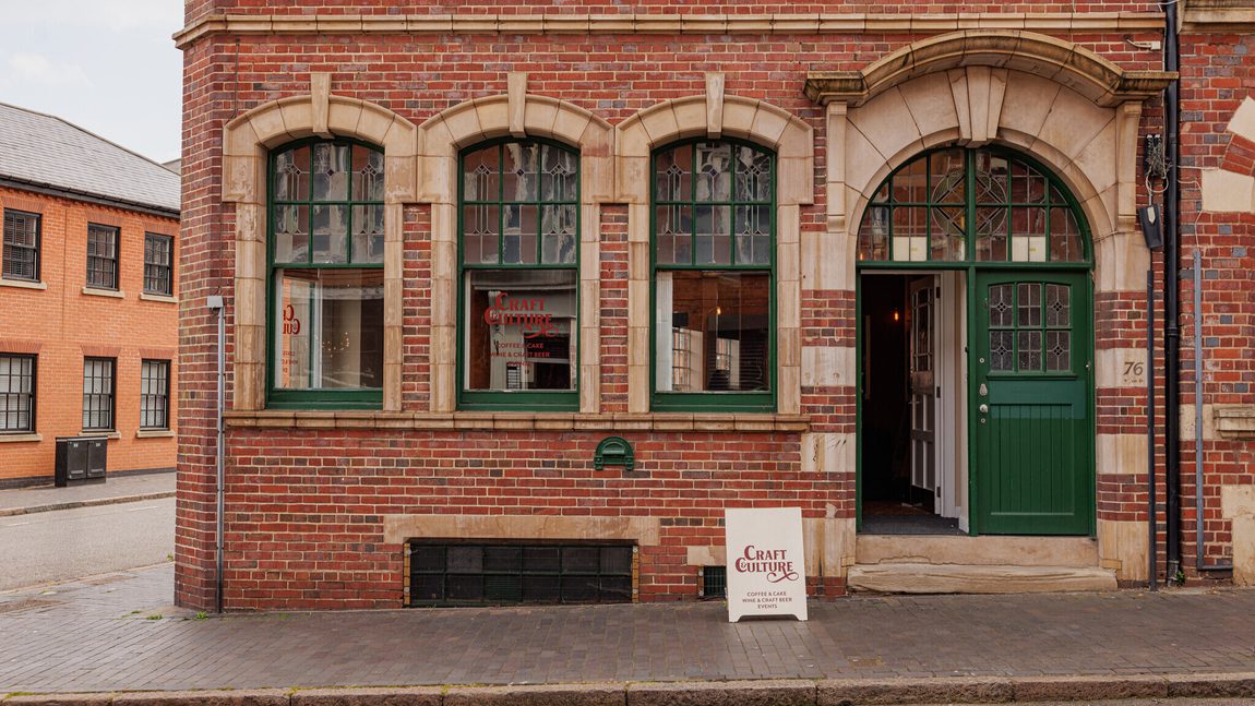 Traditional brick building with green-trimmed windows and door, featuring a Craft Culture sign.