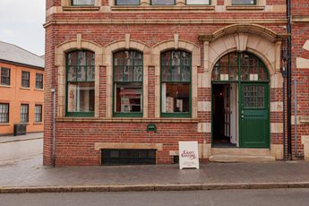 Traditional brick building with green-trimmed windows and door, featuring a Craft Culture sign.