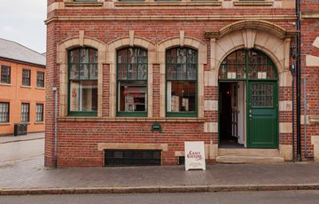 Traditional brick building with green-trimmed windows and door, featuring a Craft Culture sign.
