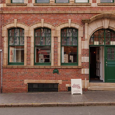 Traditional brick building with green-trimmed windows and door, featuring a Craft Culture sign.