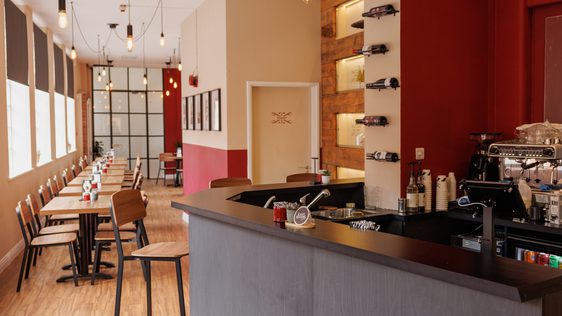 Cozy café with wooden floors, high stools, pendant lighting, and a modern coffee bar.