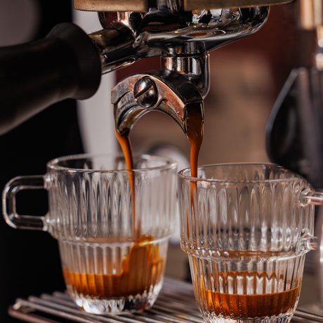 Espresso machine extracts coffee into two clear glass cups simultaneously.