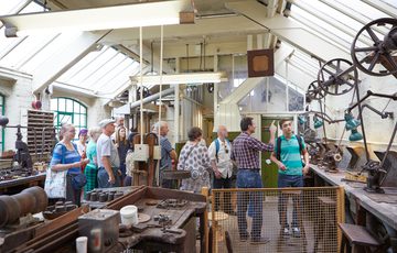 A group of people on a tour in an historic jewellery workshop.