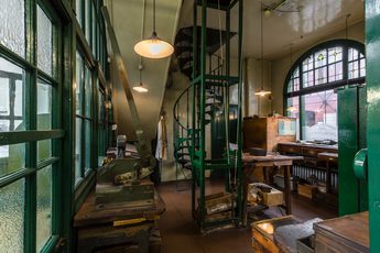An office in a historic jewellery workshop, with green windows and spiral staircase.