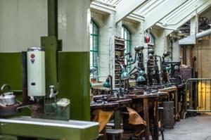 Industrial workshop benches containing anglepoise lamps, metal presses and tools of the jewellery trade