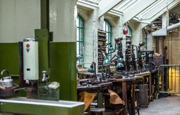 Industrial workshop benches containing anglepoise lamps, metal presses and tools of the jewellery trade