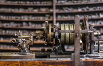 Close up of a machine with tools on shelves in the background.