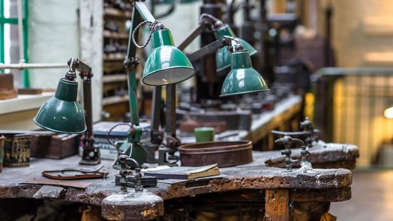 A close up of 4 lamps and tools on a workbench.